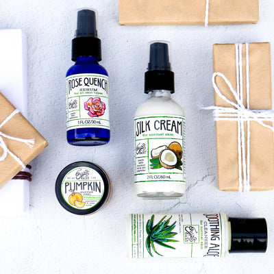 the aloe cleanser, rose serum, cream and face peel next to brown paper gifts tied with white string