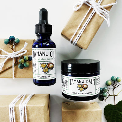 tamanu oil and tamanu balm next to brown paper packages tied up with string and blue berries