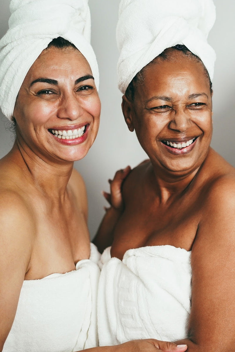 TWO WOMEN, IN THEIR 30'S - 50'S -  IN WHITE TOWELS, LAUGHING