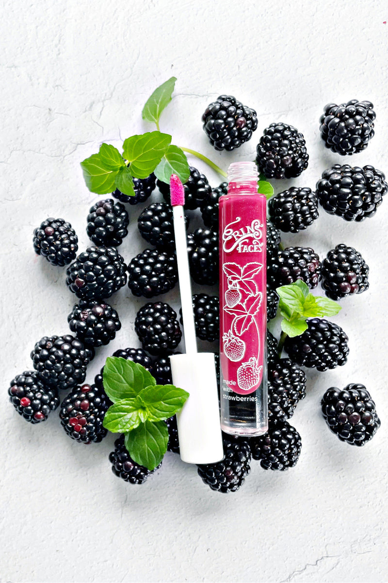 white background with blackberries and mint leaves alongside erin's faces fruit smoothie lip gloss in starbright - a deep pink shade