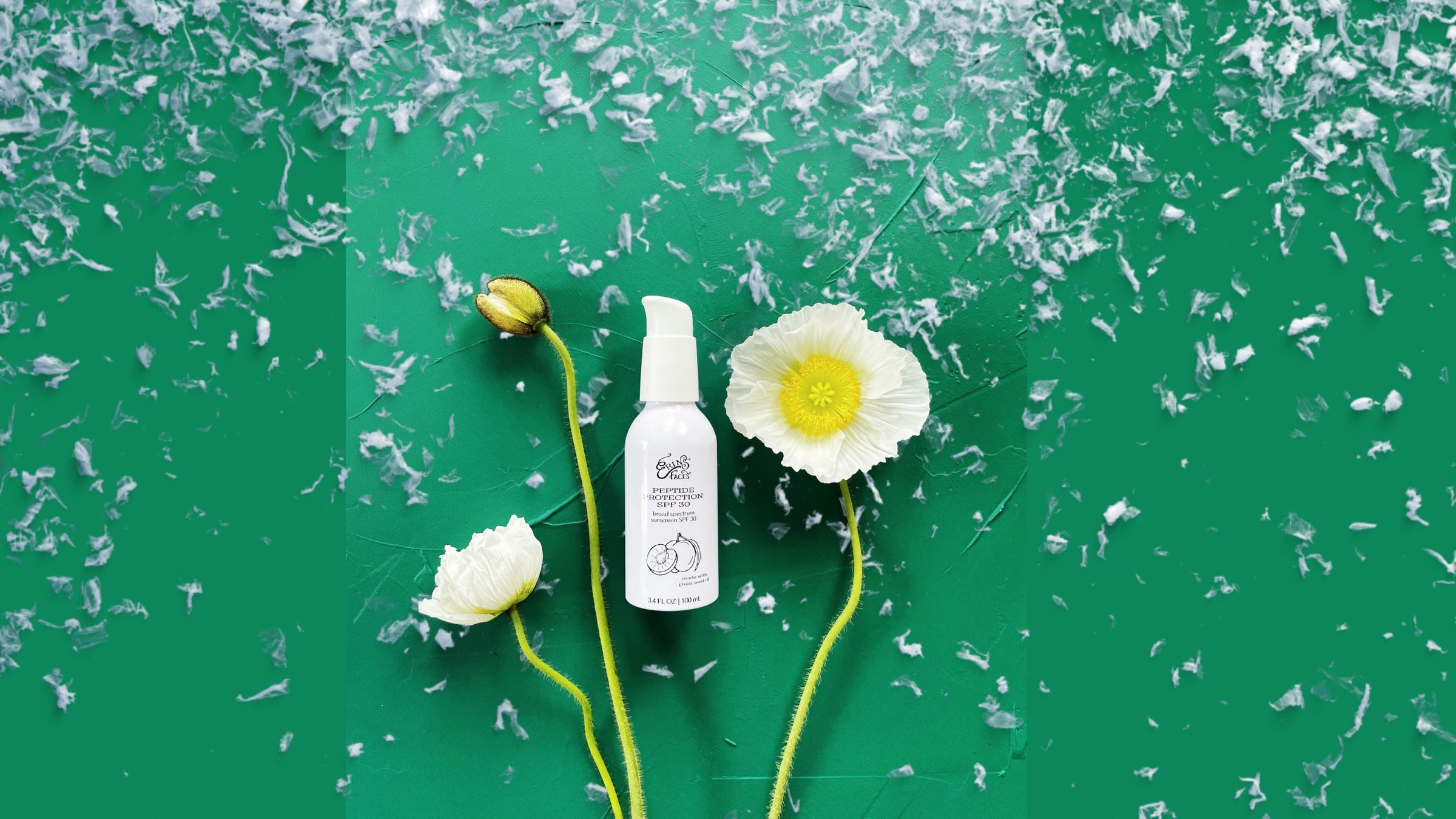 white bottle of peptide protection spf 30 with white poppies on green stems, all on a deep green background covered with soft snowflakes