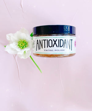 Antioxidant Facial Polish jar on pink background with white hellebore