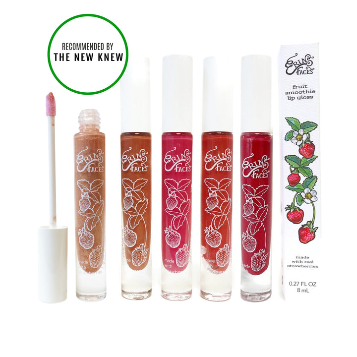 six tubes of lip gloss in various shades, with strawberries on each tube and the box the tube comes in, also with strawberries on it, of erin's faces fruit smoothie lip gloss with an inset that says "recommended by The New Knew"