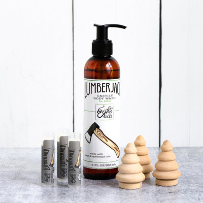 lumberjack castile body wash bottle with three lip balms next to three small wooden trees