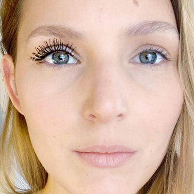 Woman's face with matcha mascara on eyelashes on one side of her face